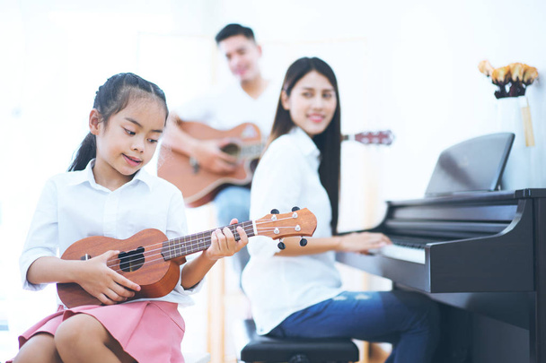 Азиатская дочь и родитель будут играть музыку в белой комнате
. - Фото, изображение