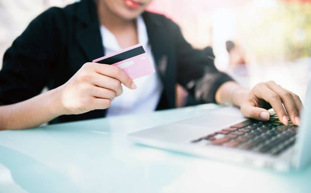 Young woman holding credit card and using laptop computer and smart phone. Online shopping concept, technology and internet concept. - Photo, Image