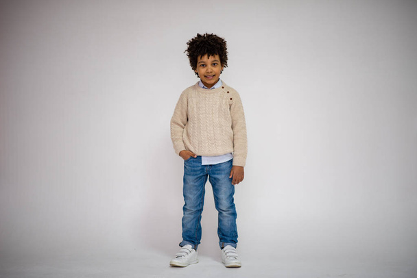 dark-skinned boy in blue jeans and in a white sweater in different poses shows different emotions on different backgrounds - Photo, image