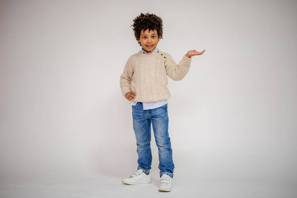 dark-skinned boy in blue jeans and in a white sweater in different poses shows different emotions on different backgrounds - Photo, image