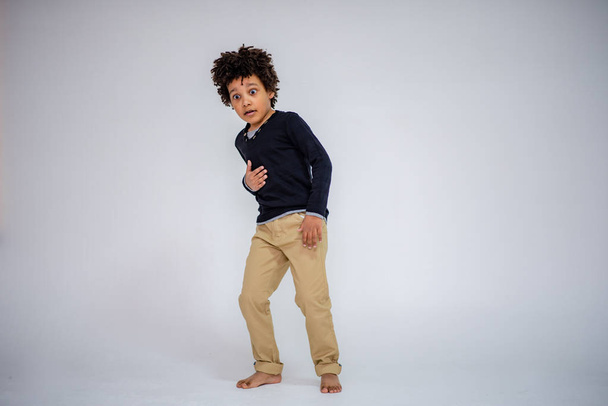 dark-skinned boy in blue jeans and in a white sweater in different poses shows different emotions on different backgrounds - Fotoğraf, Görsel