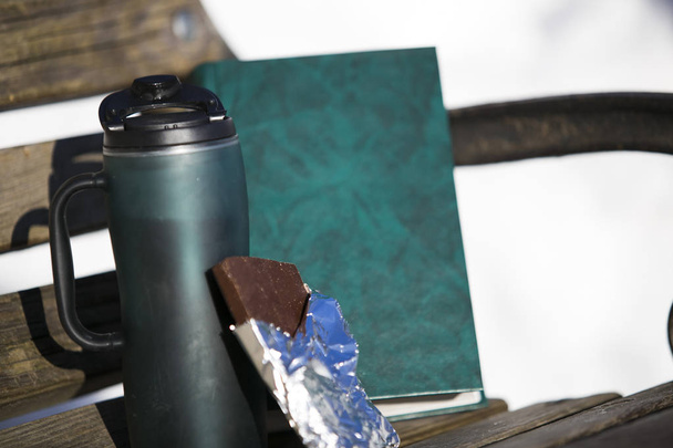 eine grüne Tasse mit Deckel, eine offene Plakette aus brauner Schokolade in einem s - Foto, Bild
