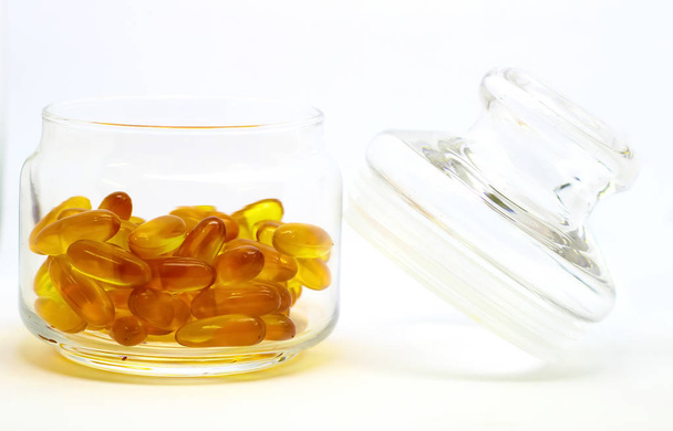 Kalanmaksaöljy omega 3-vitamiinigeelikapselit, jotka on eristetty valkoisella pohjalla läpinäkyvässä lasipullossa, jossa on lasinen kansi
 - Valokuva, kuva
