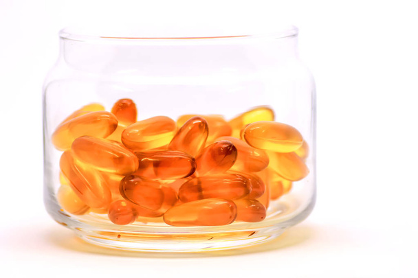 Kalanmaksaöljy omega 3-vitamiinigeelikapselit, jotka on eristetty valkoisella pohjalla läpinäkyvässä lasipullossa
 - Valokuva, kuva
