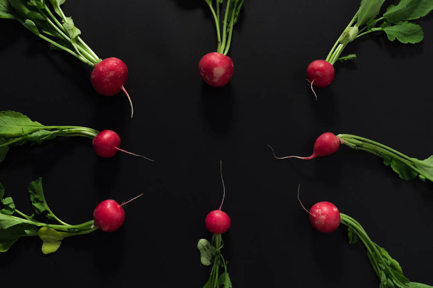 Fresh radishes on black background. Flat lay. - Фото, изображение