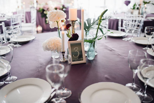 Mesa de invitados con vajilla festiva, velas, flores y número especial
 - Foto, Imagen