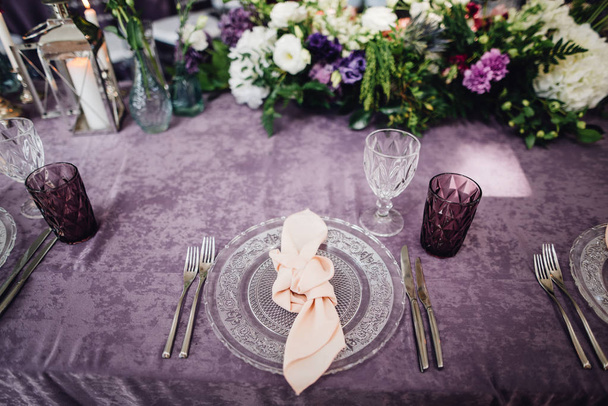 Festtafel mit reichem Geschirr und Blumen auf Tisch mit Veilchentuch - Foto, Bild