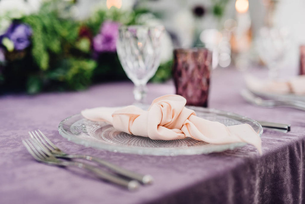 Mesa festiva que sirve con vajilla rica y flores en la mesa con paño violeta
 - Foto, imagen