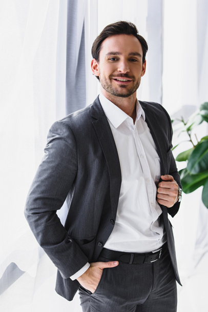 smiling handsome businessman looking at camera in office - Foto, afbeelding