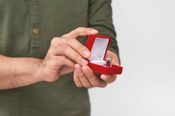 Fechar as mãos masculinas segurando anel de casamento e caixa de presente
. - Foto, Imagem