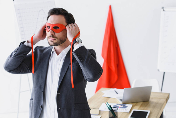 Super zakenman koppelverkoop rode masker in kantoor  - Foto, afbeelding