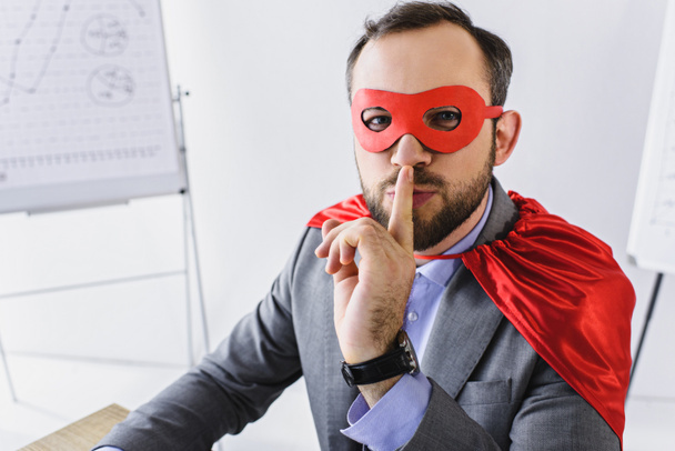 super businessman in mask and cape showing silence sign in office  - Photo, Image