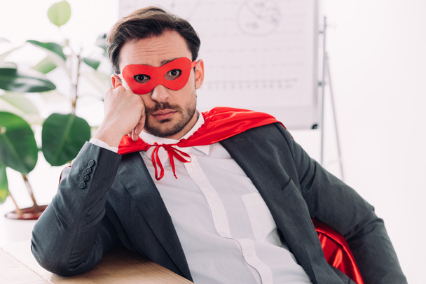 verbaasd super zakenman in masker en cape kijken camera in kantoor - Foto, afbeelding