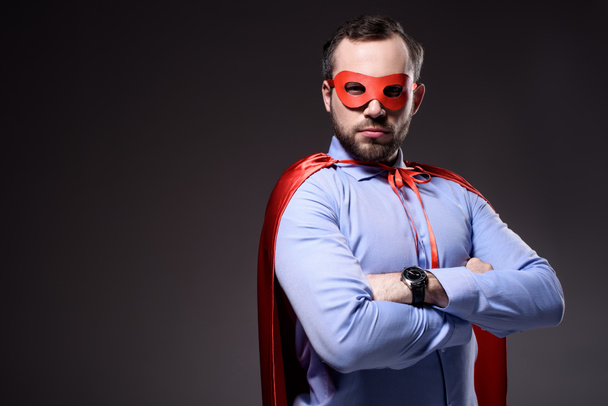 handsome super businessman in mask and cape with crossed arms isolated on black - Zdjęcie, obraz