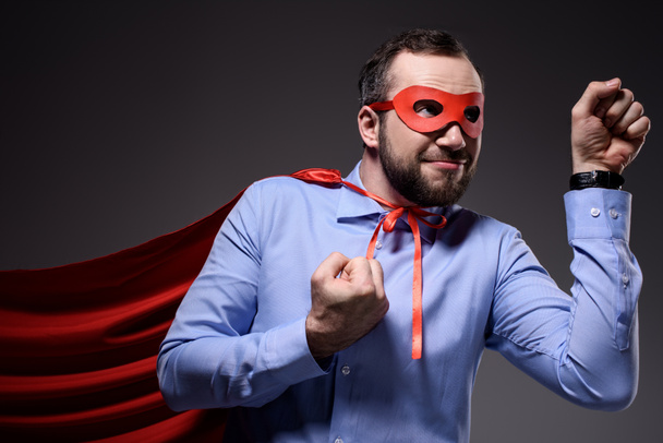 smiling handsome super businessman in mask and cape showing fists isolated on black - Photo, Image