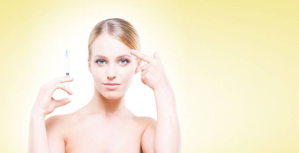 Young, beautiful and healthy woman having skin injections over yellow background. Plastic surgery concept. - Zdjęcie, obraz