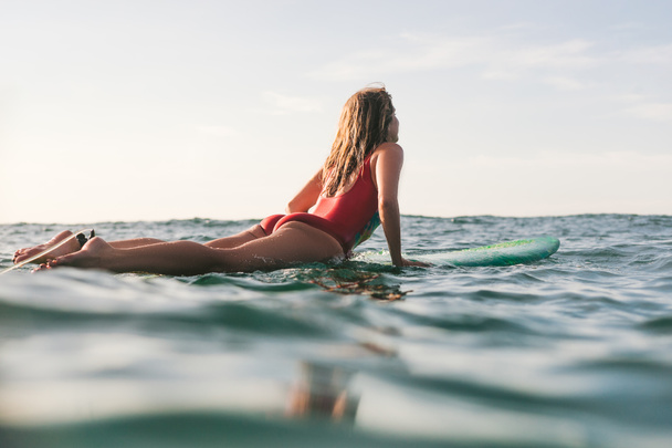 woman in swimming suit surfing alone in ocean on sunny day - Fotoğraf, Görsel