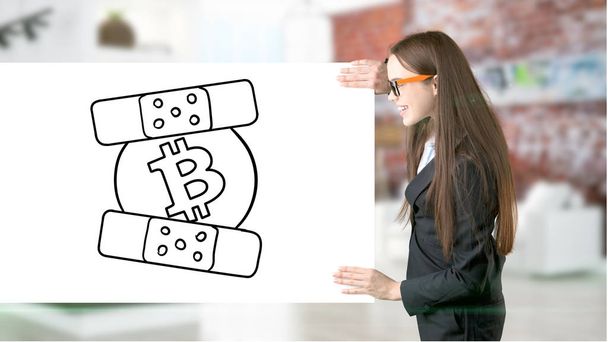 Surprised smiling young woman wearing a suit and looking at a cryptocurrency sketch on a design flat wall. Concept of Bitcoin risk. - Foto, afbeelding