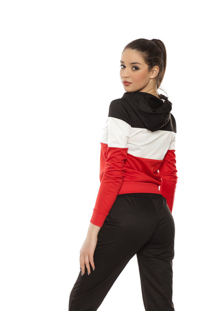 junge schöne Frau in schwarz-roten Trainingsanzügen auf weißem Hintergrund - Foto, Bild