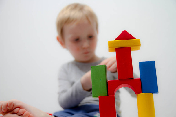 Mały chłopiec trzech lat siedzi na stole i gra z plas - Zdjęcie, obraz