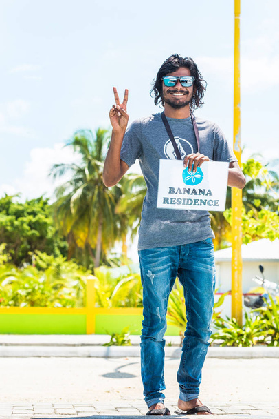 Μάλε, Μαλδίβες - Νοεμβρίου 27, 2016: Χαμογελαστός άνθρωπος με ένα σημάδι. Αντιγράψτε το χώρο για το κείμενο. Κάθετη. - Φωτογραφία, εικόνα