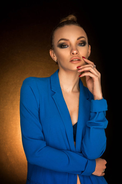 Beautiful young girl in blue jacket with beauty makeup in studio - Fotó, kép