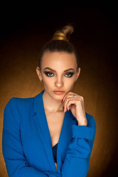 Beautiful young girl in blue jacket with beauty makeup in studio - Фото, зображення