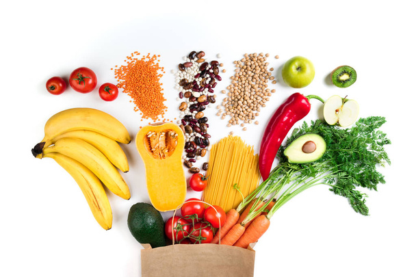 Fondo alimentario saludable. Comida vegetariana saludable en bolsa de papel pasta, verduras y frutas en blanco. Compras concepto de comida
 - Foto, Imagen