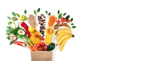Healthy food background. Healthy vegetarian food in paper bag pasta, vegetables and fruits on white. Shopping food concept - Photo, Image