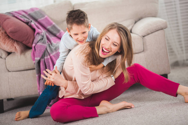 Young mother playing with son on floor at home in living room - Foto, Imagem