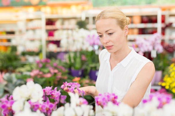 Beautiful lady smelling colorful blooming orchids. - 写真・画像