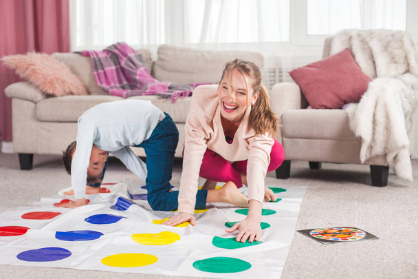 mother playing twister with son in living room - Foto, afbeelding