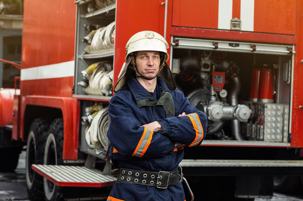 Palomies (palomies) toiminnassa seisoo lähellä paloauto. Hätätilanne. Suojelu, pelastus vaaroilta
. - Valokuva, kuva