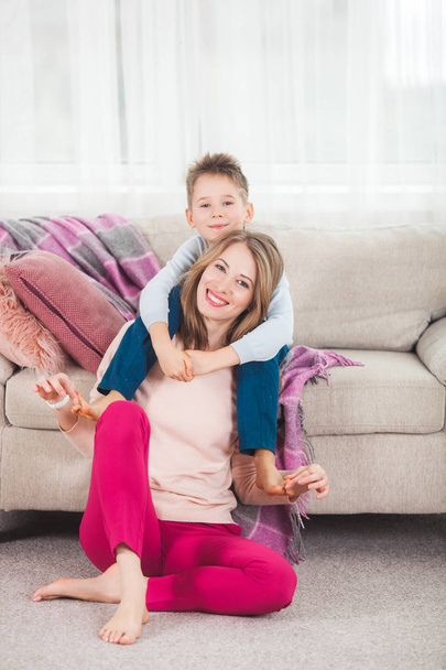 Young mother having fun with son in livingroom at home - Foto, imagen