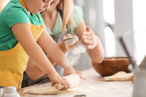 Mother with daughter sifting flour on dough on kitchen - Foto, Bild