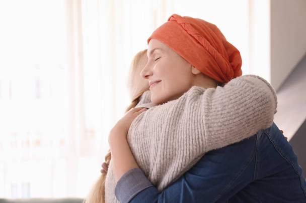 Young woman with cancer hugging her mother indoors - Fotoğraf, Görsel