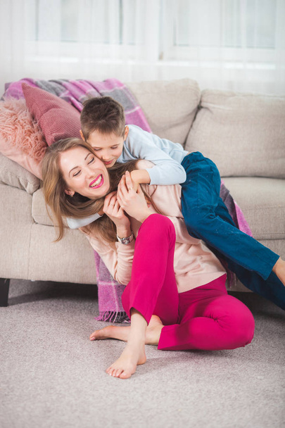 junge Mutter spielt mit Sohn zu Hause im Wohnzimmer auf dem Boden - Foto, Bild