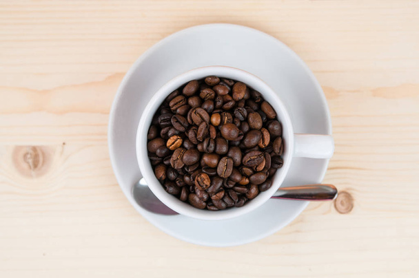 Закрыть кофе, чашку, кофейную фасоль, серебряную ложку на деревянном столе
. - Фото, изображение