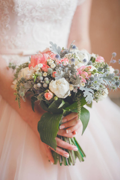 Bride holding fresh wedding bouquet with roses and dried flowers - Fotó, kép