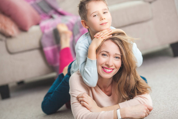 Young mother playing with son on floor at home in living room - Photo, Image