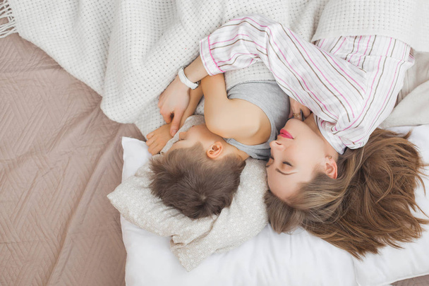 Μητέρα στον ύπνο με γιο στο κρεβάτι κάτω από την κουβέρτα λευκό  - Φωτογραφία, εικόνα
