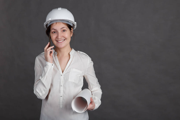 Девушка-инженер в защитном шлеме разговаривает по телефону
 - Фото, изображение