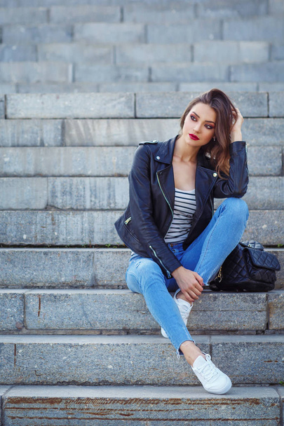full length portrait of stylish woman sitting on concrete stair outdoor - 写真・画像