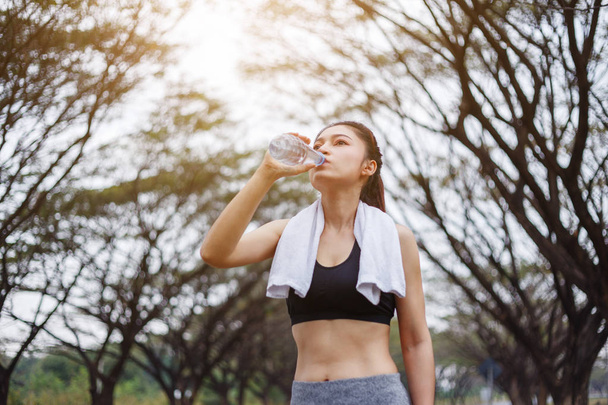Sportieve jongedame drinkwater in park - Foto, afbeelding