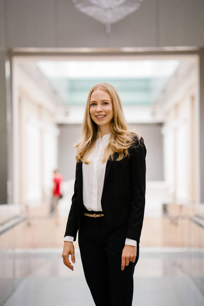 Portrait of an expatriate, caucasian white woman in a smart black suit with white shirt in an office background. She is confident and is a European expatriate in Asia. - Fotografie, Obrázek