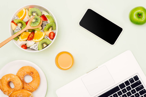 Υγιή επιχειρηματική μεσημεριανό στο γραφείο, φρούτα μπολ σαλάτας και laptop σε λευκό φόντο. - Φωτογραφία, εικόνα