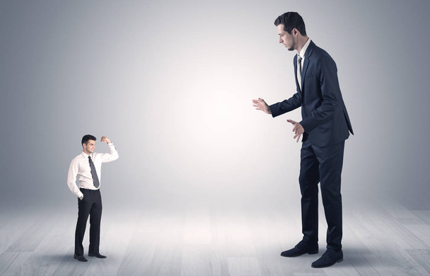 Giant businessman scared of small businessman - 写真・画像