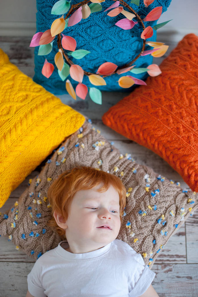 The boy is resting on crocheted pillows - Фото, изображение