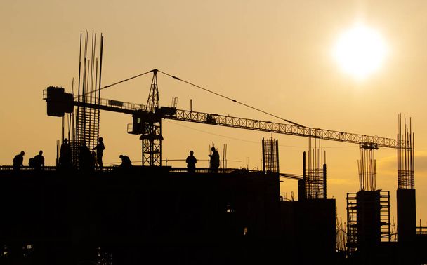 Groep van werknemers op de bouwplaats bij zonsondergang - Foto, afbeelding