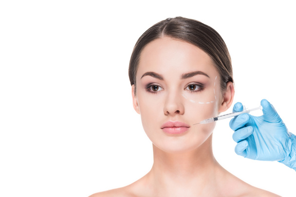 mooie jonge vrouw met een stippellijn getekend op gezicht voor plastische chirurgie nemen schoonheid injectie geïsoleerd op wit - Foto, afbeelding